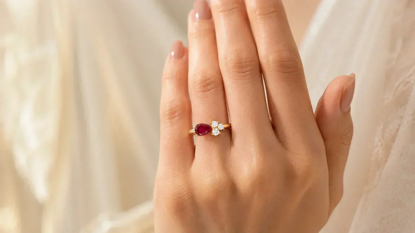 East-West pear-cut ruby engagement ring set horizontally across the finger